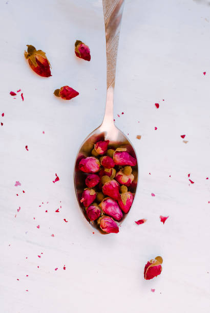 istock Dried tea rose buds in a spoon on a light background, Close-up. 1249625301