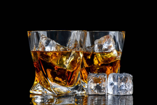 istock Glass of whiskey with cube ice on black background 1249626193