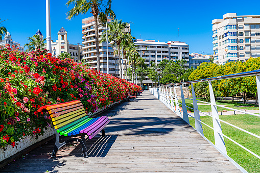 Rainbow colored public park bench at Flowers Bridge, Valencia-Spain. Sunny day. High resolution 42Mp outdoors digital capture taken with SONY A7rII and Zeiss Batis 25mm F2.0 lens