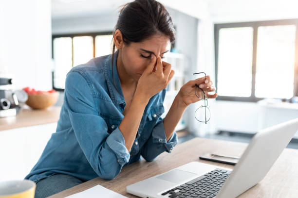 beklemtoonde bedrijfsvrouw die van huis op laptop werkt die ongerust, vermoeid en overweldigd kijkt. - stress stockfoto's en -beelden
