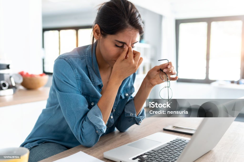 Stressed business woman working from home on laptop looking worried, tired and overwhelmed. Shot of stressed business woman working from home on laptop looking worried, tired and overwhelmed. Emotional Stress Stock Photo