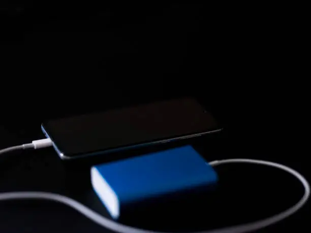 Photo of Close up of a Smart Phone Charging on a Black Table