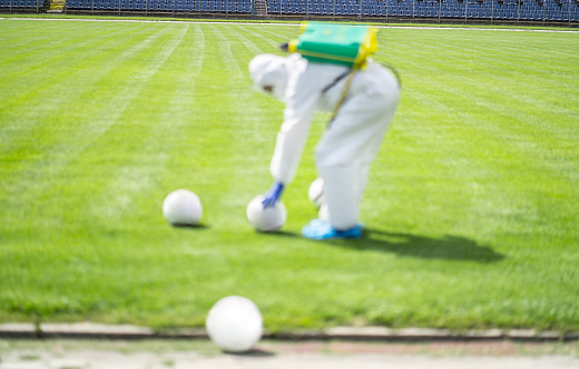 Service staff by disinfecting and cleaning the football balls on the sport field