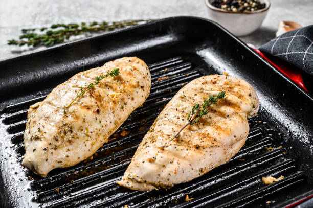 istock grilled chicken breast in a pan with thyme and garlic. gray background. Top view 1249631695