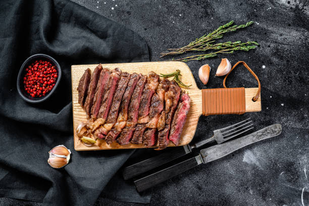 istock Grilled rib eye, ribeye steak on a chopping Board, medium rare. marbled meat. black background. top view 1249633085