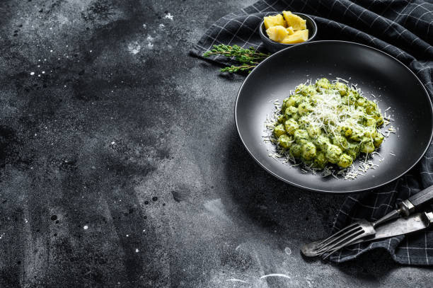 istock Gnocchi with basil spinach sauce and Parmesan. Italian potato paste. Black background. Top view. Copy space 1249634171