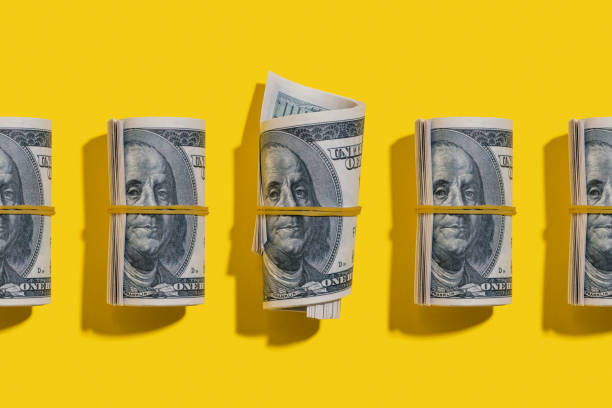 il dollaro americano rotola piatto sdraiato su sfondo giallo - knolling concetto foto e immagini stock