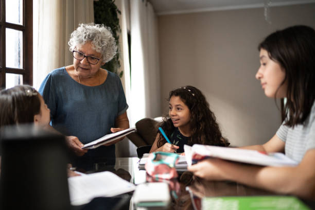 istock Grandmother helping granddaughter with homework while they studying at home 1249636410