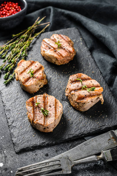 istock grilled pork steak tenderloin with fresh herbs. black background. Top view 1249636582
