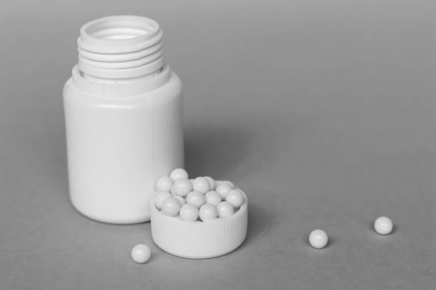 istock Capsules in the lid with plastic jar on a grey background 1249638115