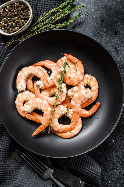 istock Cooked peeled king prawns, shrimps on a plate. Black background. Top view 1249640391