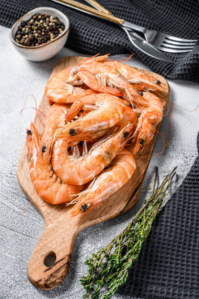 istock Cooked fresh giant prawns on a wooden chopping Board. White background. Top view 1249640420
