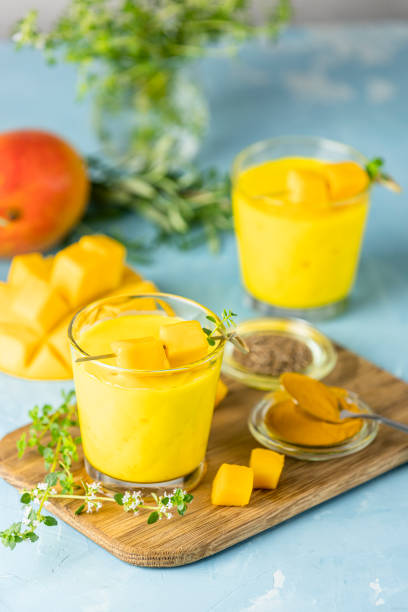 Yellow Indian mango yogurt drink Mango Lassi or smoothie with turmeric and saffron. Healthy probiotic Indian cold summer drink on blue background.
