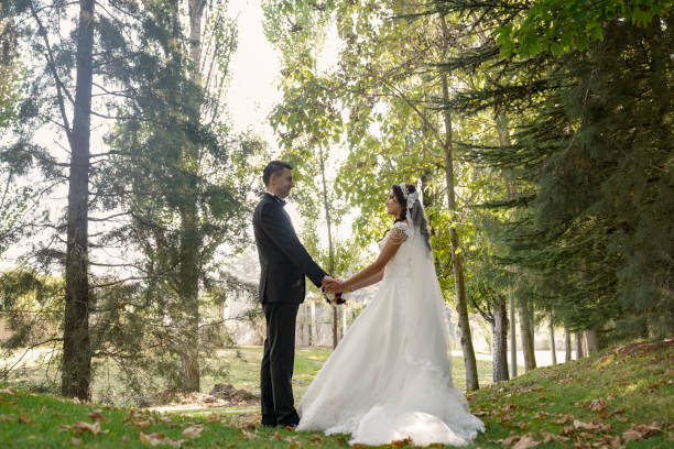 istock Bride and groom walking on the grass and holding hands in a park 1249641636