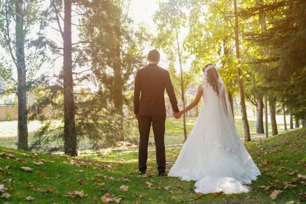 istock Bride and groom walking on the grass and holding hands in a park 1249641637