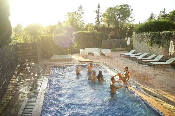 Girlfriends with inflatable rings jumping in the swimming pool