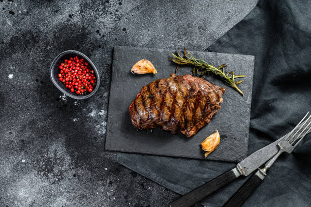 istock Grilled Top Blade steak on a stone Board, marbled beef. Black background. Top view 1249641811