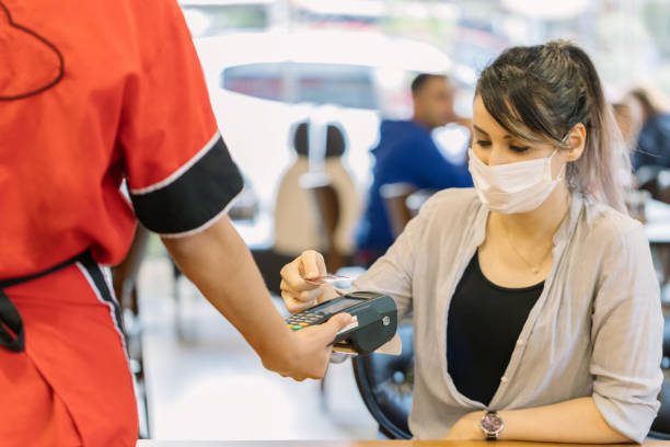 istock Young woman making a contactless payment in a restaurant 1249642022