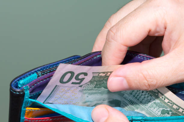 istock Close up of hands pulling  banknotes 50 dollar out of wallet. 1249643964