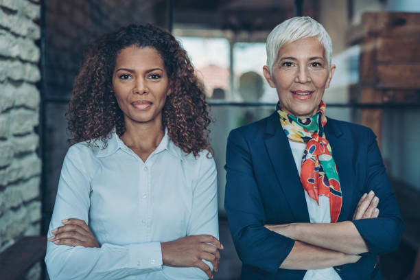 Businesswomen standing together side by side Portrait of two businesswomen looking at camera racial equality photos stock pictures, royalty-free photos & images