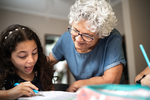 Grandmother helping granddaughter with homework while he's studying at home