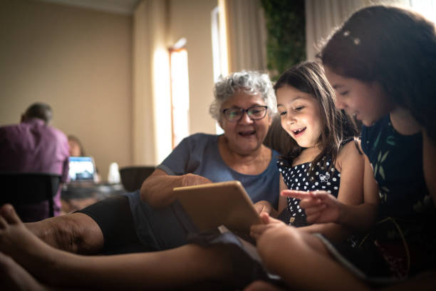 grandmother and granddaughter on a video call with a digital tablet at home - senior adult technology child internet imagens e fotografias de stock