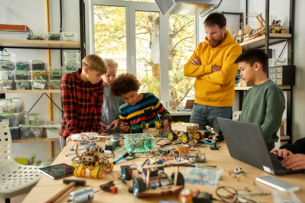 istock Our challenge is our progress. Young technicians building a robot vehicle together with a male teacher at a stem robotics class. Inventions and creativity for kids 1249654484