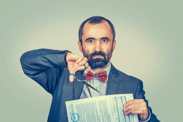istock Image of man cutting a document with scissors. Cancel a contract concept. 1249657789