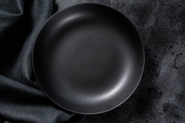 istock Black plate and a towel on textured black background.  Top view. Copy space 1249658565