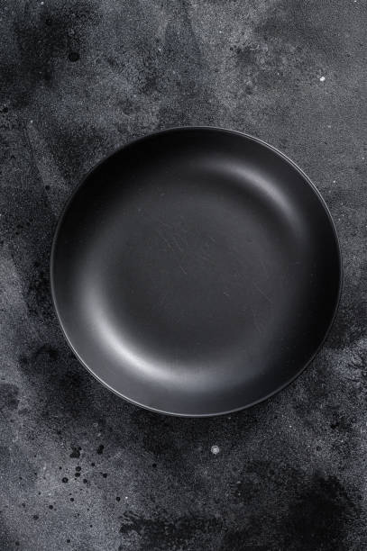 istock Black plate on textured black background.  Top view. Copy space 1249659335