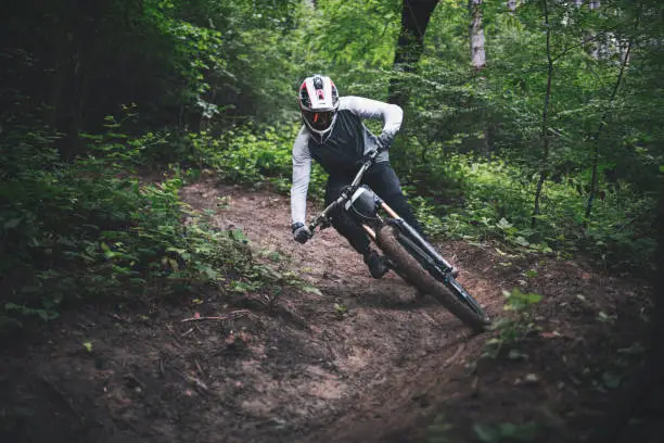 Mountain biker rides downhill in the professional downhill trail.