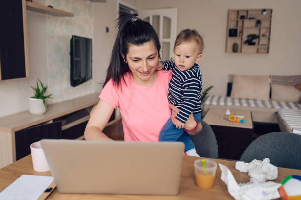 istock Young mother freelancing and holding her baby 1249667744