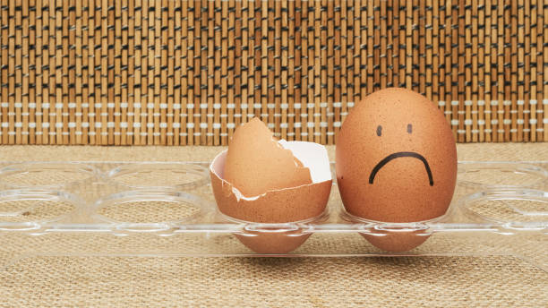 istock Chicken eggs in an egg holder. Full tray of eggs. Half an egg, egg yolk, shell. Emotion and facial expression painted on eggs. 1249669061