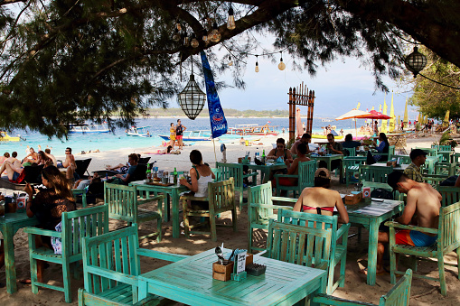 Gili Trawangan, Lombok, Indonesia - August 12th of 2019: Tourists have a meal or take a bath in the amazing spot of the harbor beach of the largest Gili Island.