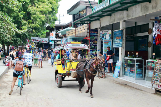 Tourists, locals, bicycles, carriages,  and horses mixed in the sand promenade that rounds the largest Gili Island. Gili Trawangan, Lombok, Indonesia - August 14th of 2019: Tourists, locals, bicycles, carriages,  and horses mixed in the sand promenade that rounds the largest Gili Island. gili trawangan stock pictures, royalty-free photos & images