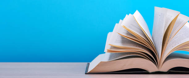 istock The book is open, lying on the table, sheets fanned out on a blue background. 1249696142