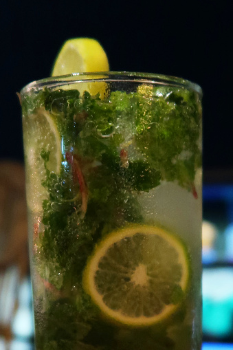 Stock photo showing close-up of a non alcoholic Virgin Mojito mocktail /cocktail with ice, mint in glass with slice of lemon and mint sprigs.