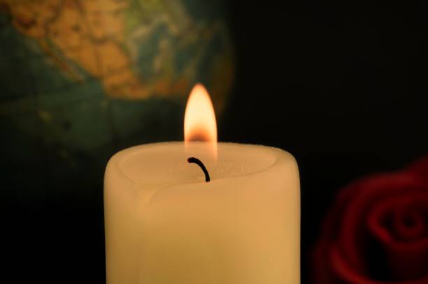 istock Burning yellow wax candle, globe and roses 1249700095