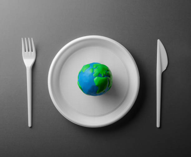 istock Serving table with colored Earth planet and black and white plastic plate, fork and knife. Ecology Concept for Earth Hour, Earth Day, Ocean Day and other ECO dates. 1249705593