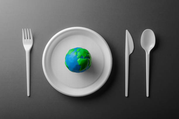 istock Serving table with colored Earth planet and black and white plastic plate, spoon, fork and knife. Ecology Concept for Earth Hour, Earth Day, Ocean Day and other ECO dates. 1249705719