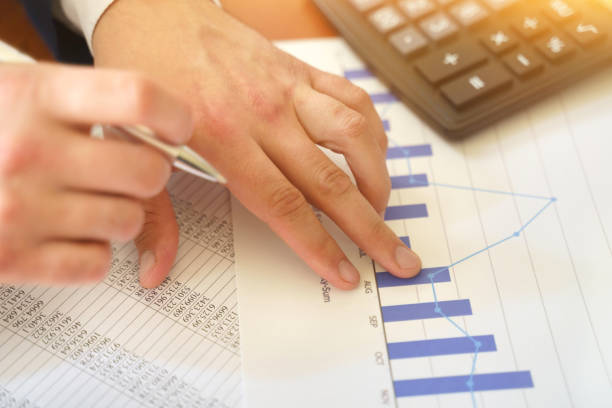 istock Male hand with a calculator and pen, business graph and chart. 1249708904