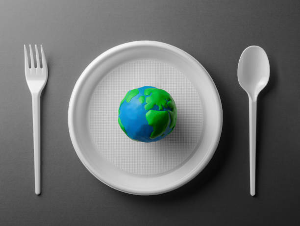 istock Serving table with colored Earth planet and black and white plastic plate, spoon and fork. Ecology Concept for Earth Hour, Earth Day, Ocean Day and other ECO dates. 1249711892