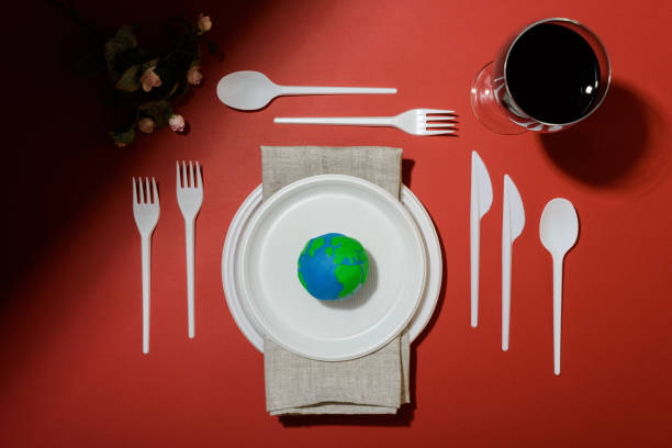 istock Serving table with Earth planet, plastic plates, spoons, forks, knives, serviette and wine glass with petroleum oil. Ecology Concept for Earth Hour, Earth Day, Ocean Day and other ECO dates. 1249712341