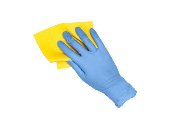 istock Latex disposable blue glove holding yellow microfiber cloth isolated on white. 1249713205