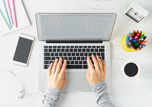 Work from home, online shopping, learning. White desk, old table. Top view. Distance education. Woman hands typing on laptop. Freelancer, Digital nomad concept