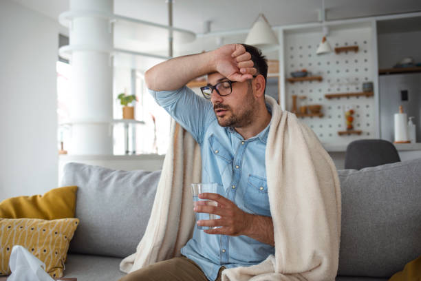 istock Shot of a young man sitting on his bed while feeling unwell at home. 1249720514