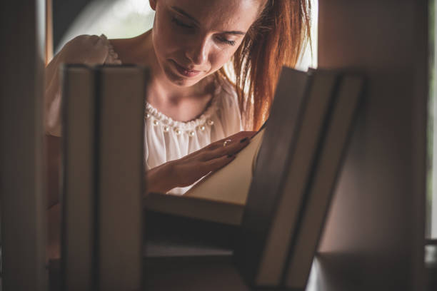 istock Young woman looking through book pages before reading it 1249727323