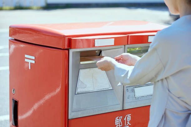 Hand of a young woman putting an envelope in a post box