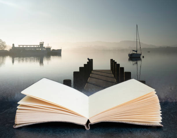istock Digital composite concept image of open book wth Stunning unplugged fine art landscape image of sailing yacht sitting still in calm lake water in Lake District during peaceful misty Autumn Fall sunrise 1249727810