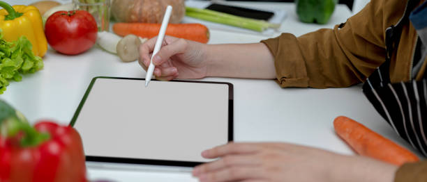 istock Female looking recipe on mock-up tablet while preparing fresh vegetables ingredients 1249733505